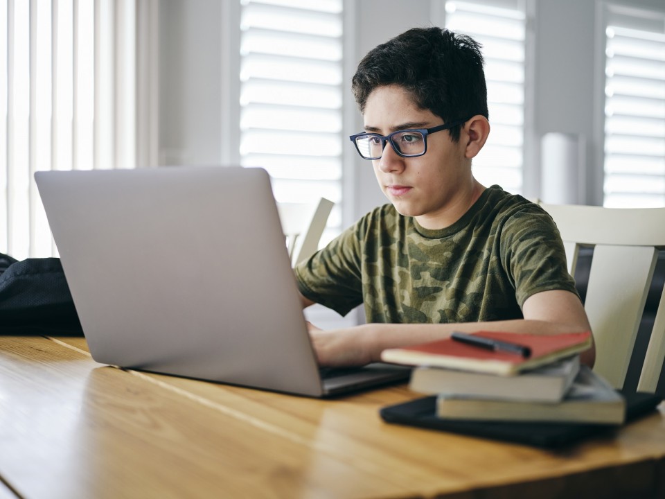 A student learning by doing schoolwork at home using a computer.